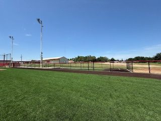 A baseball field with a fence and a blue sky in the background.