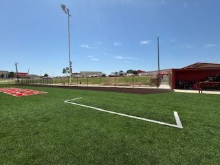 A baseball field with a white line on the grass and a dugout.