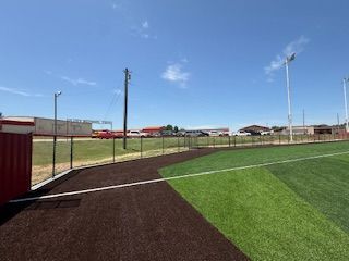 A baseball field with a fence around it and a blue sky in the background.