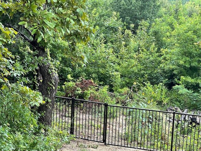 A metal fence surrounds a dirt path in the middle of a forest.