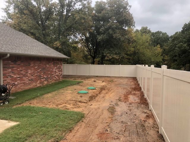 There is a white fence in the backyard of a house.