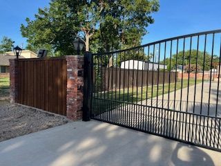 A black metal gate with a wooden fence behind it.