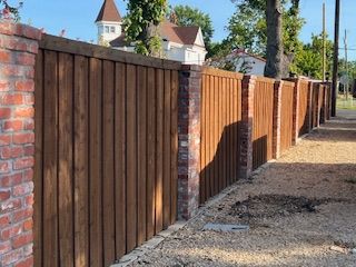 A wooden fence is surrounded by brick pillars.