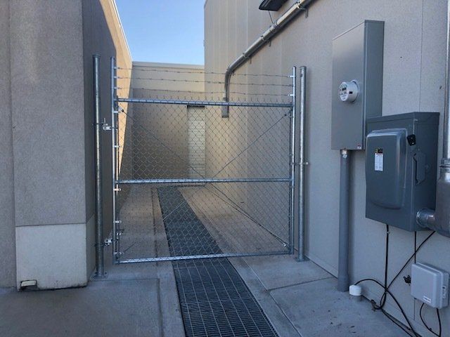 A chain link fence is between two buildings