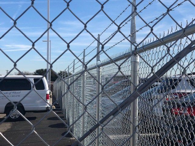 A white van is parked behind a chain link fence