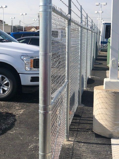 A white truck is parked behind a chain link fence.