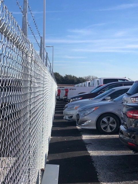 A parking lot with cars parked behind a chain link fence
