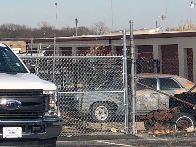 A ford truck is parked in front of a chain link fence