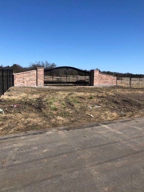 A brick wall with a gate in the middle of a field.