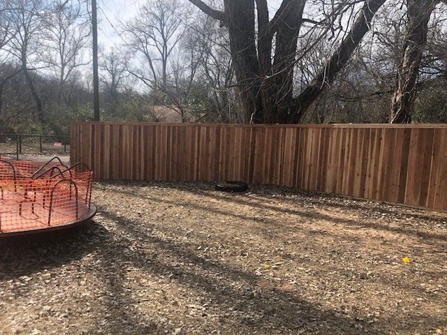 A wooden fence is in the middle of a dirt field.