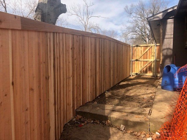 A wooden fence with a gate in the backyard of a house.