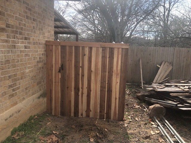 A wooden fence is sitting next to a brick wall.