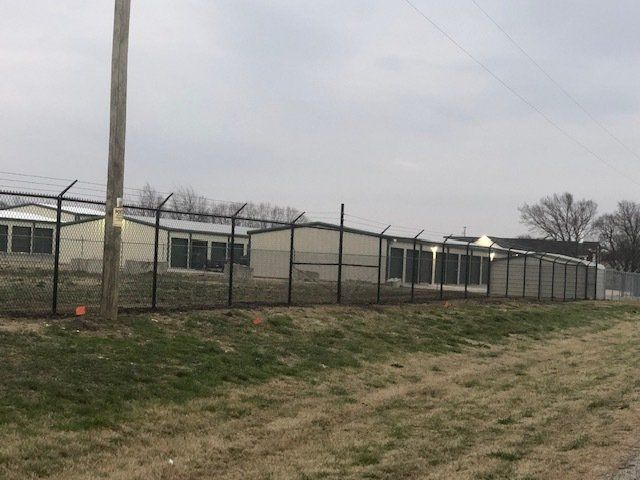 A fence surrounds a row of storage units.