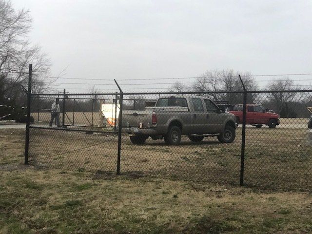 A truck is parked in front of a chain link fence.