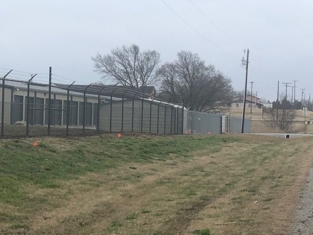 A fence surrounds a building in a grassy field.
