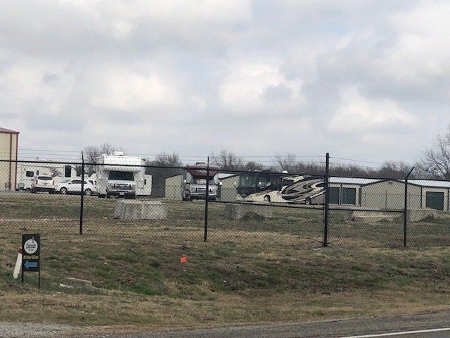 A fenced in area with a lot of rvs parked in it.
