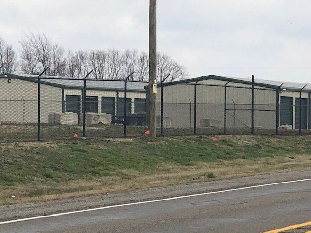 A fence surrounds a building next to a highway.