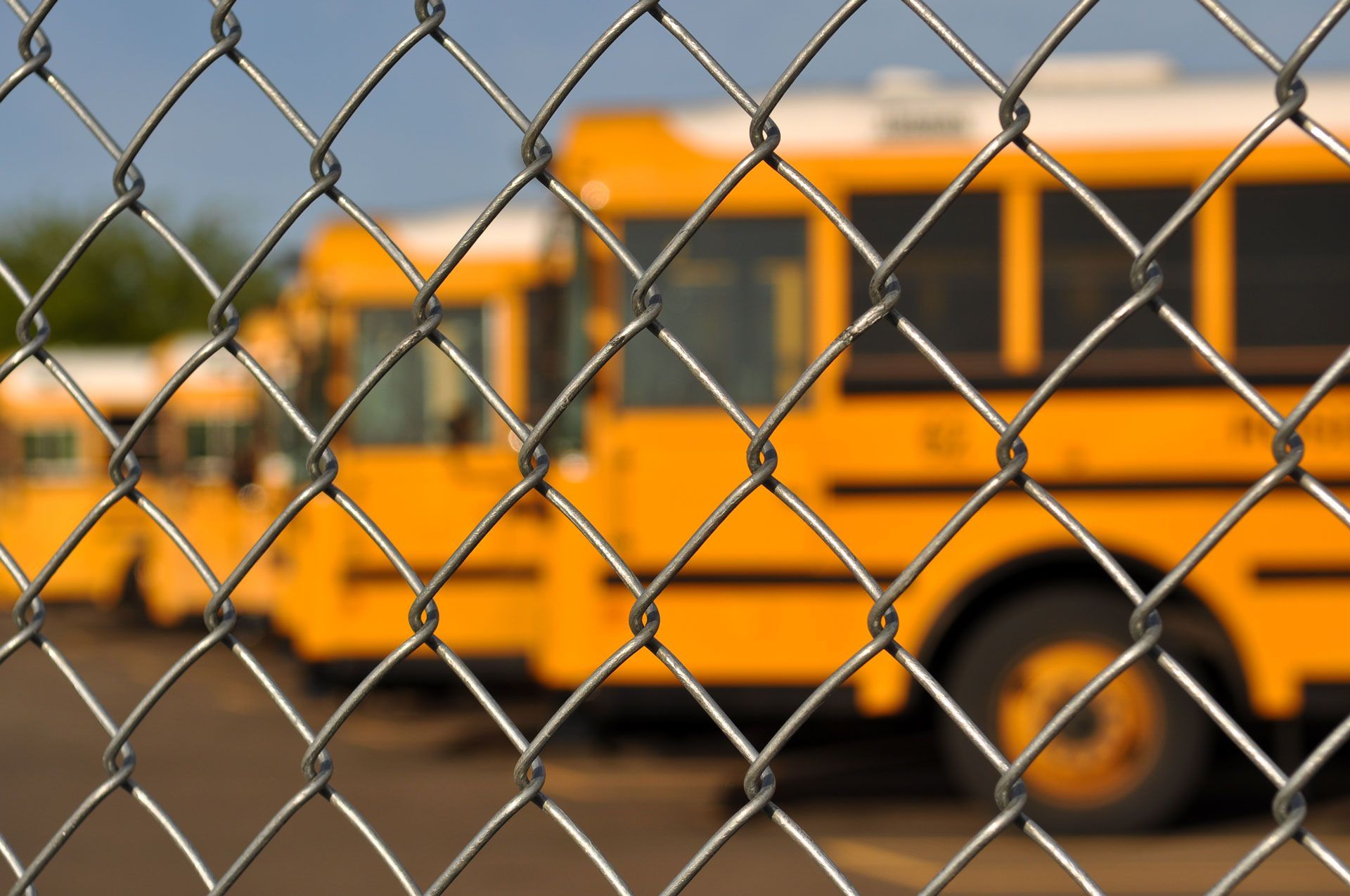 A chain link fence with a school bus in the background