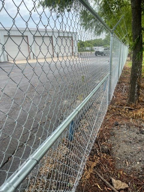 A chain link fence is surrounding a parking lot.