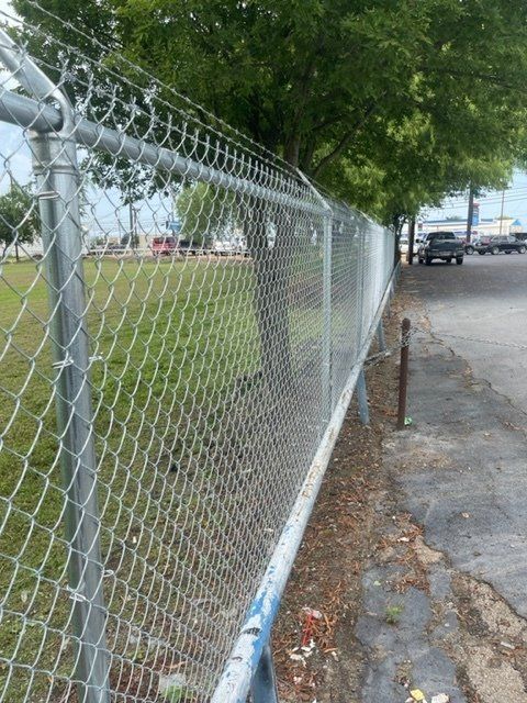 A chain link fence is along the side of a road.
