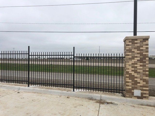 A metal fence with a brick pillar in front of it