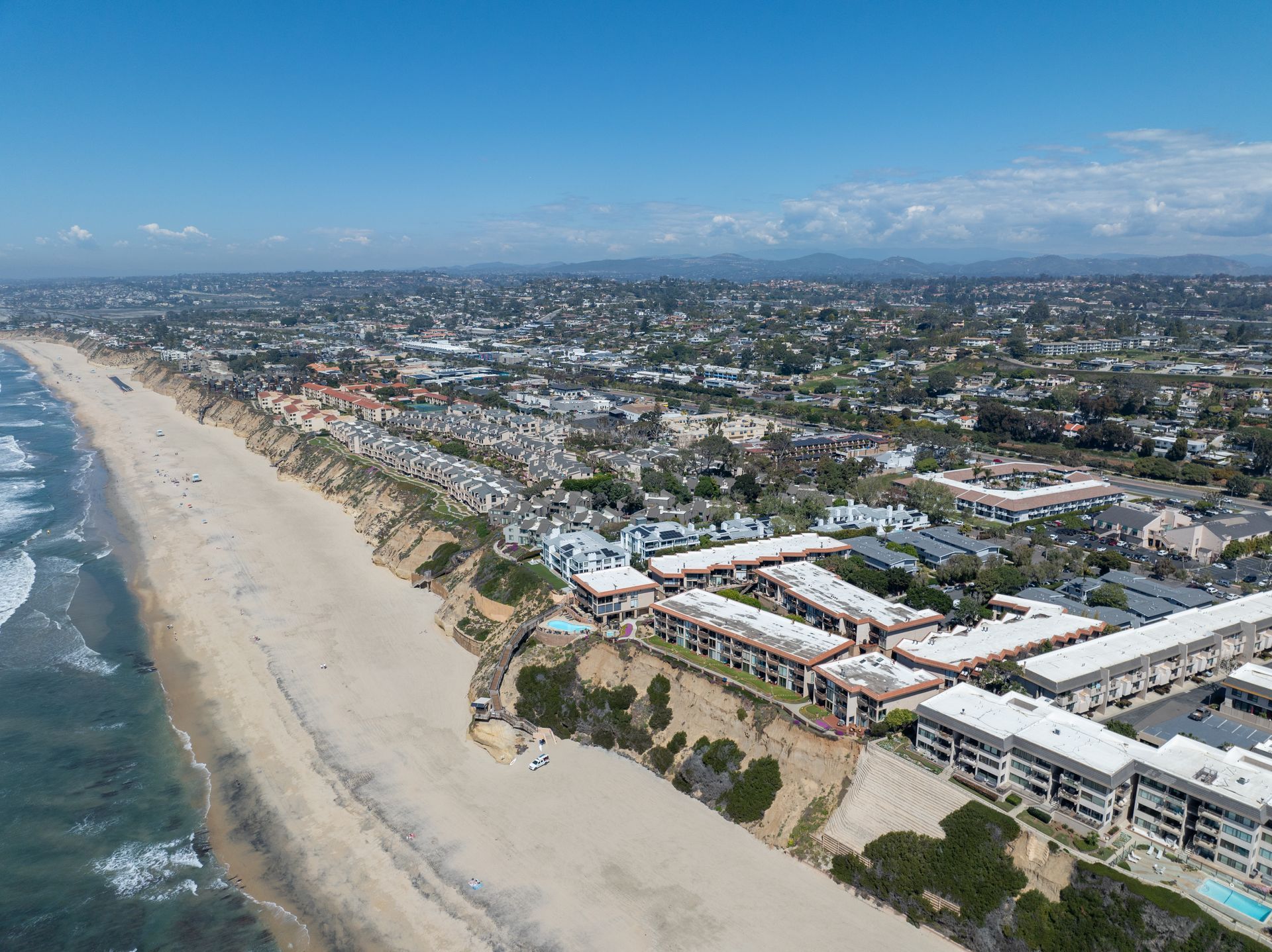 An aerial view of a beach with buildings and a city in the background.