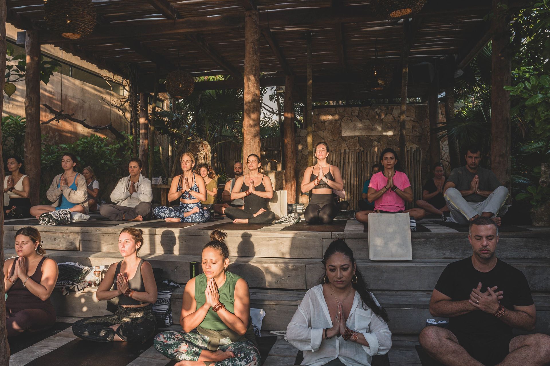 A group of people are sitting on the steps of a building doing yoga.
