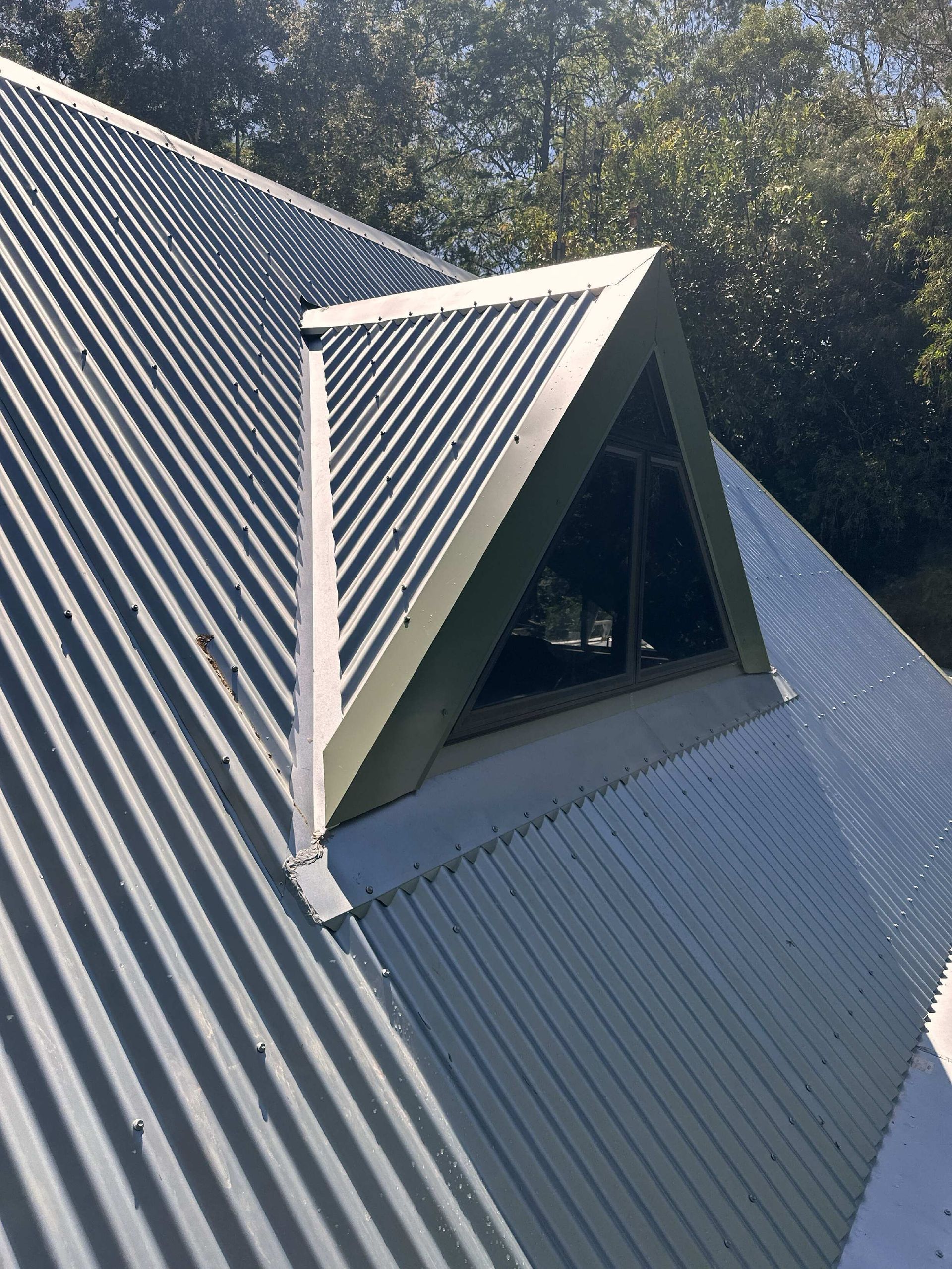 A Person Wearing Yellow Gloves Is Working On A Roof — Coastal Roof & Gutter Services In Coolum Beach, QLD