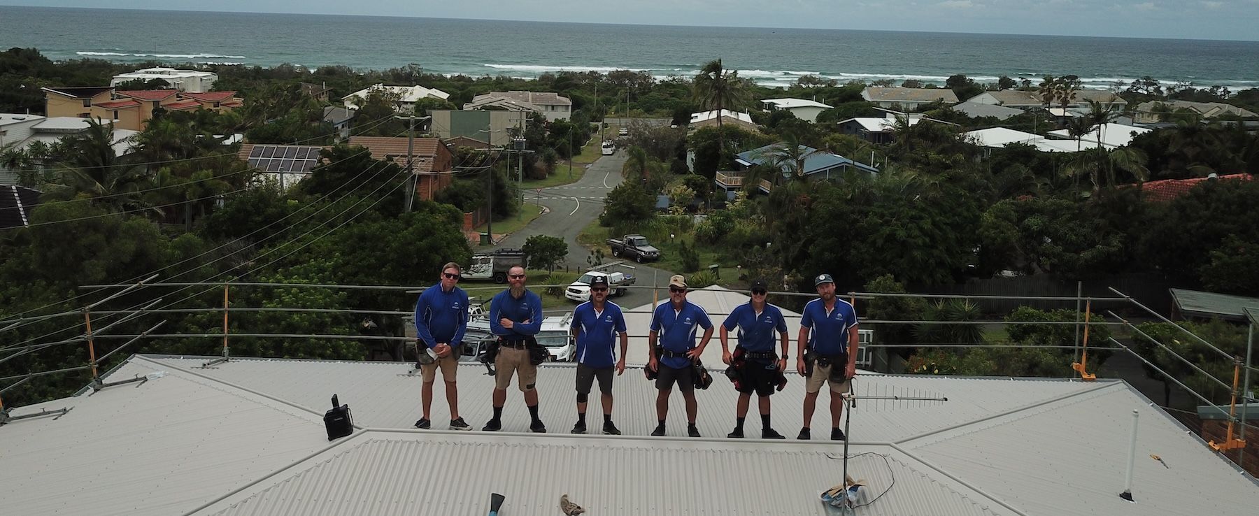 A Man Wearing Yellow Gloves Is Working On A Roof — Coastal Roof & Gutter Services In Coolum Beach, QLD