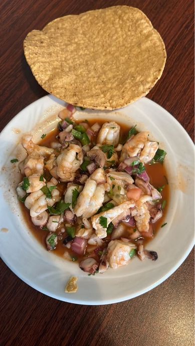 A plate of food with a tortilla on top of it on a table.