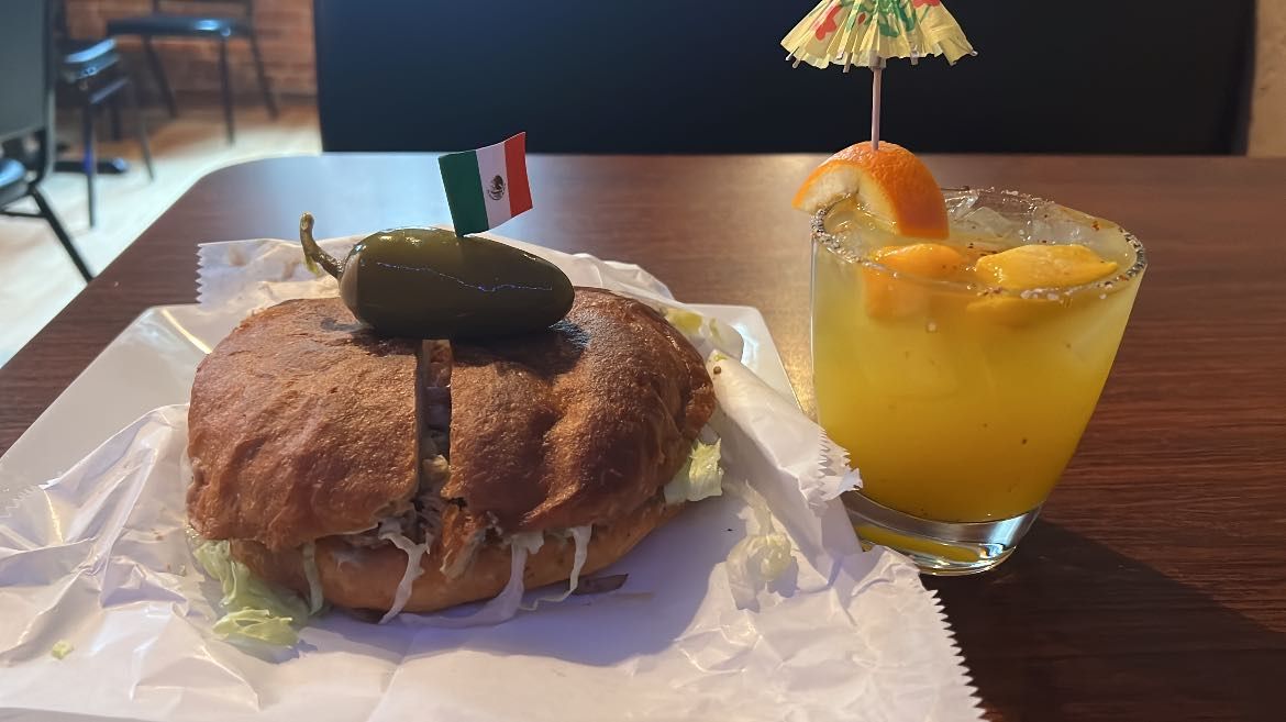 A sandwich and a drink are on a table.