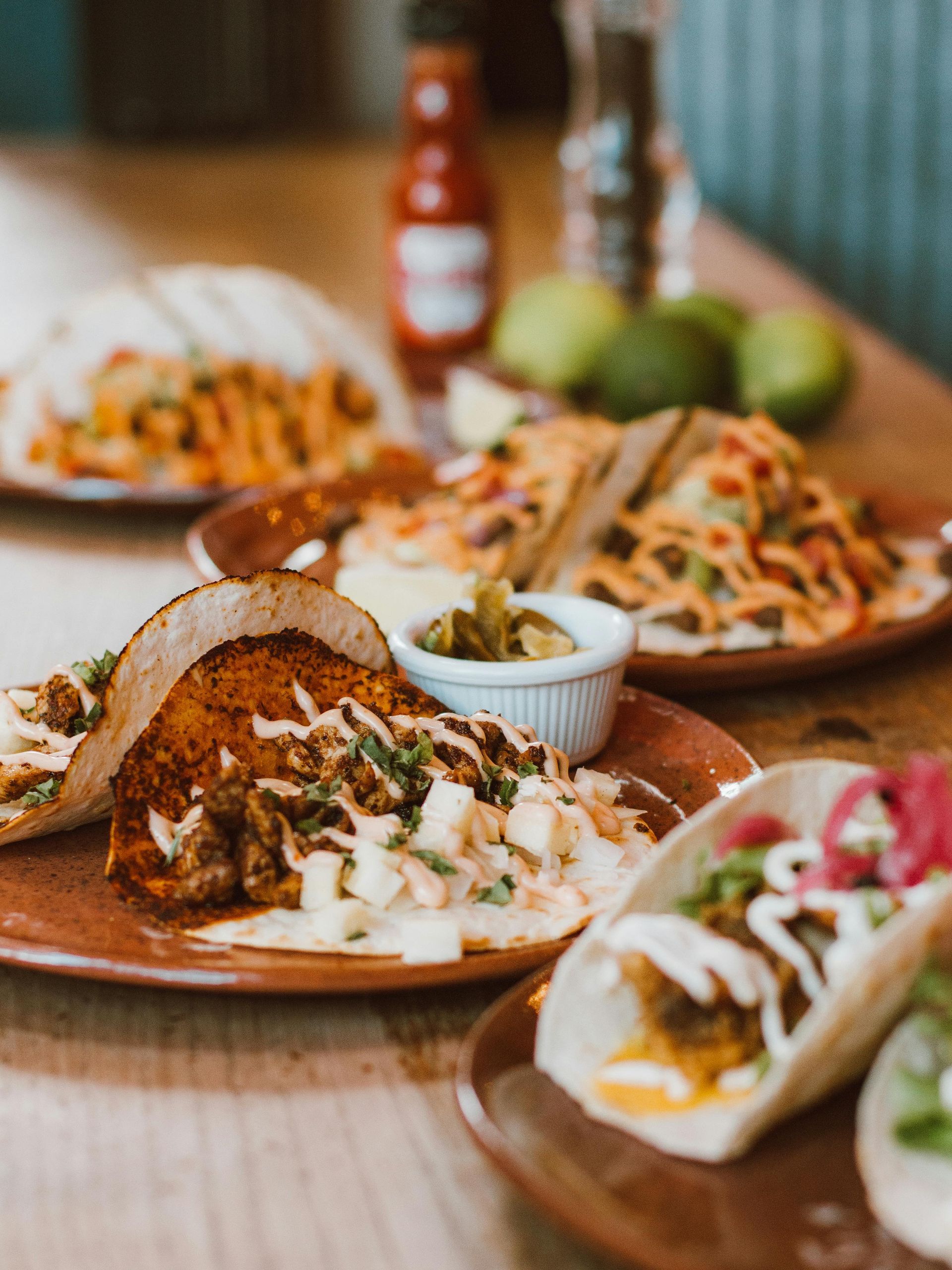 A table topped with plates of tacos and other food.