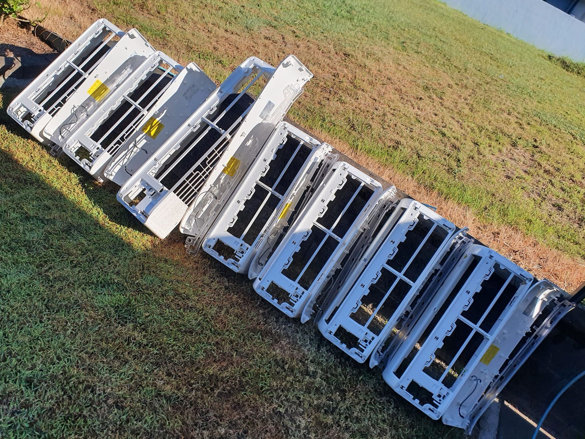 A White Air Conditioning Units Lined up On Grass — Coach That Cleans in Speewah, QLD