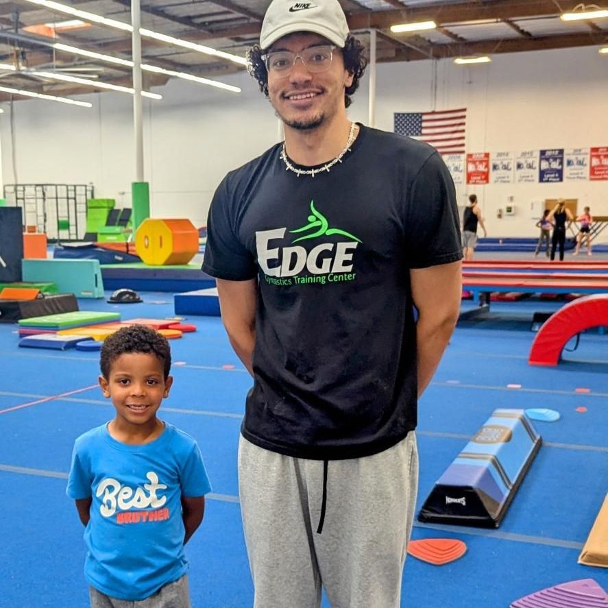 A man wearing a black shirt that says edge stands next to a boy wearing a blue shirt that says best