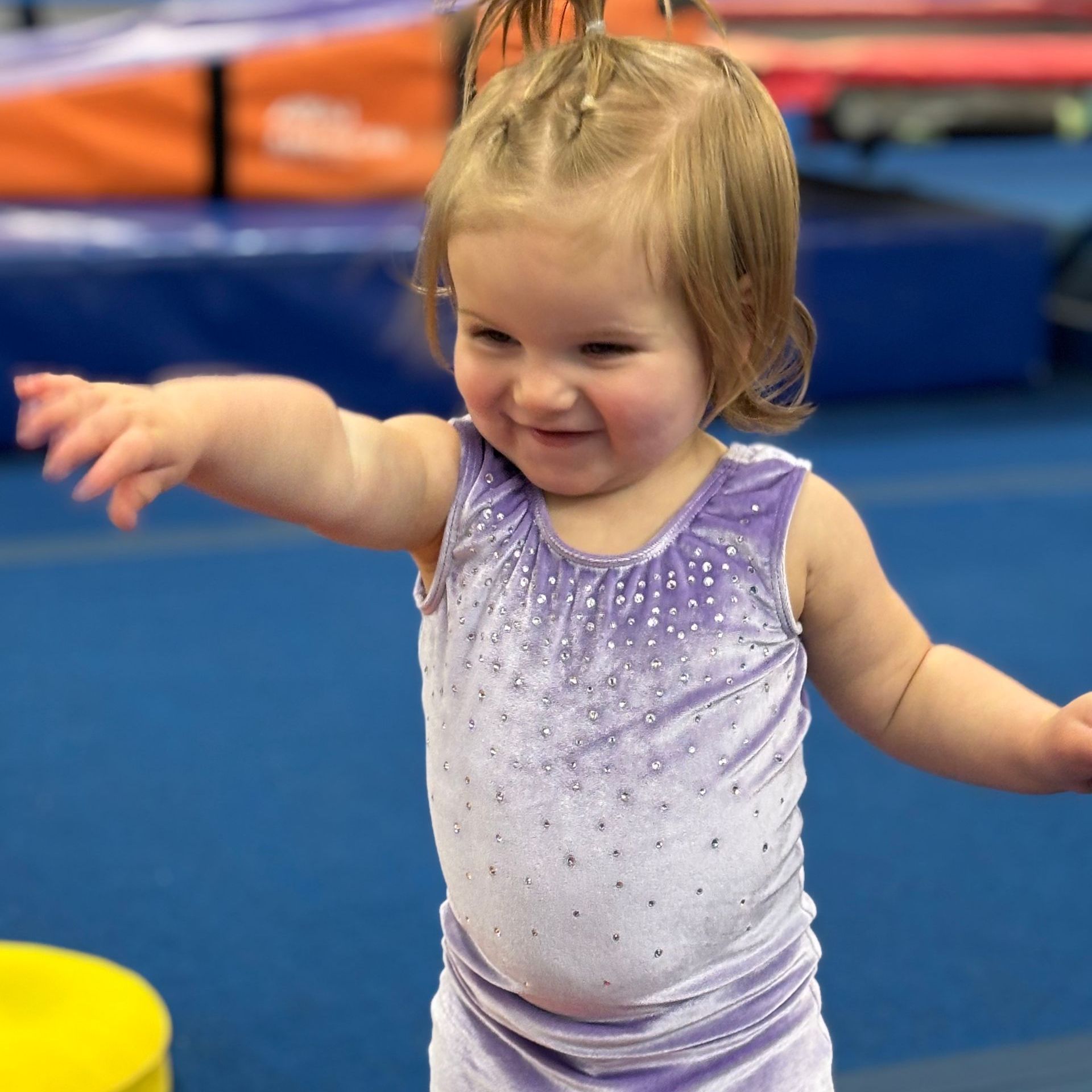 A little girl in a purple tank top is smiling