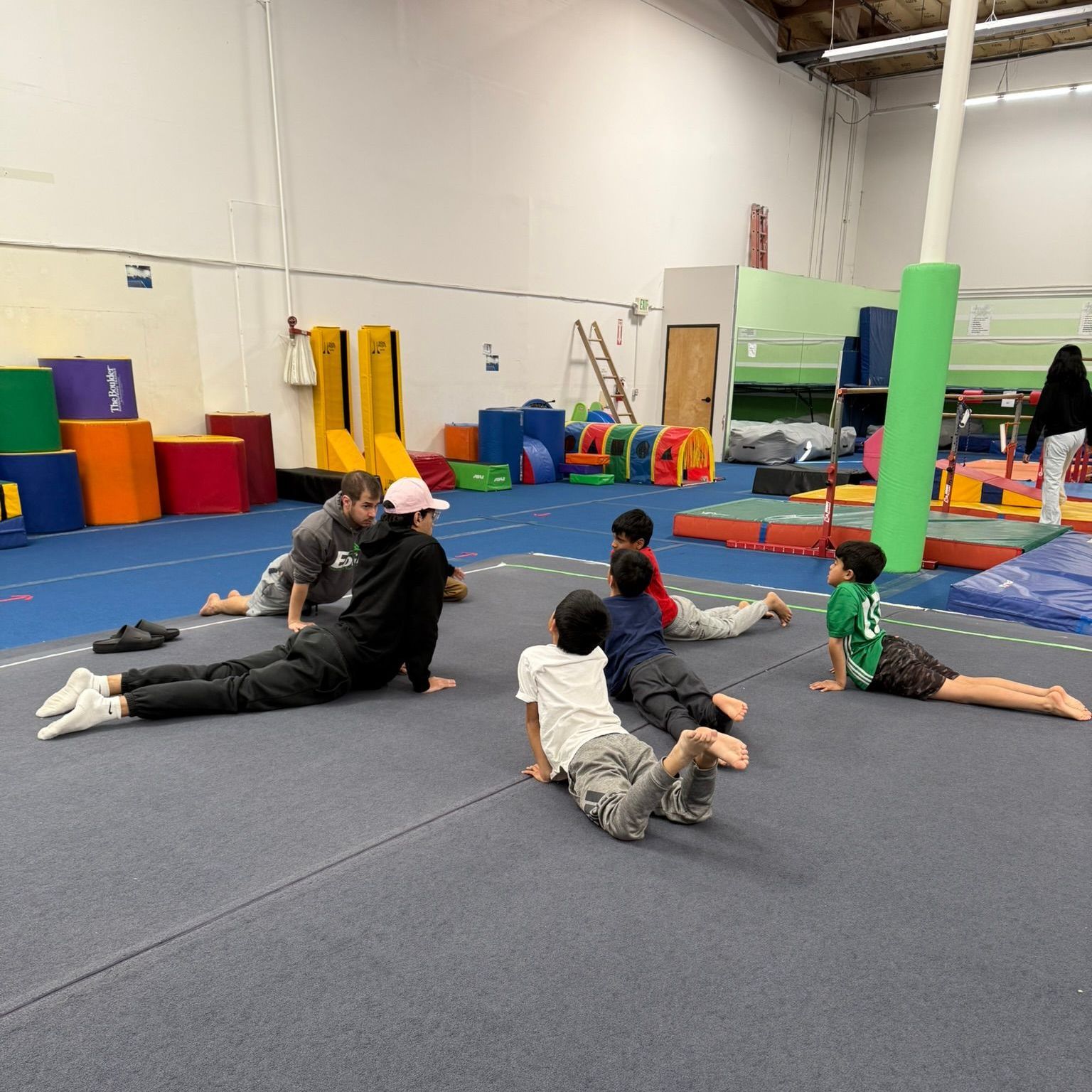 A group of children are laying on the floor in a gym