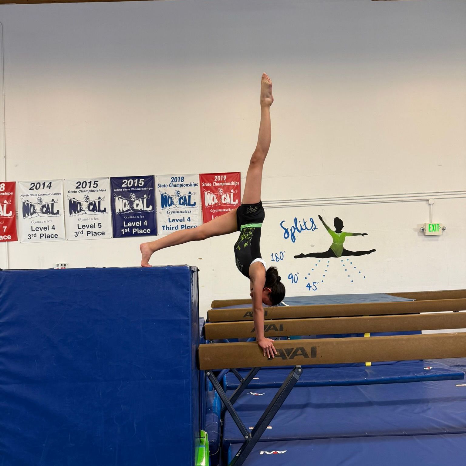 A gymnast is doing a handstand on a balance beam