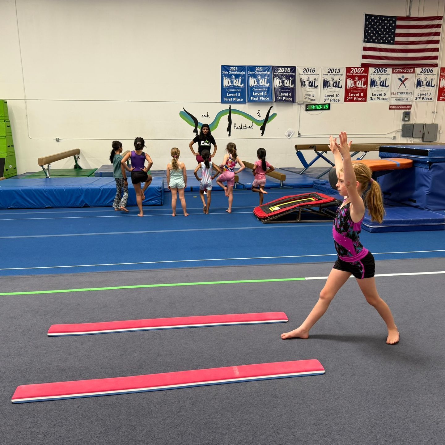 A group of young girls are practicing gymnastics in a gym