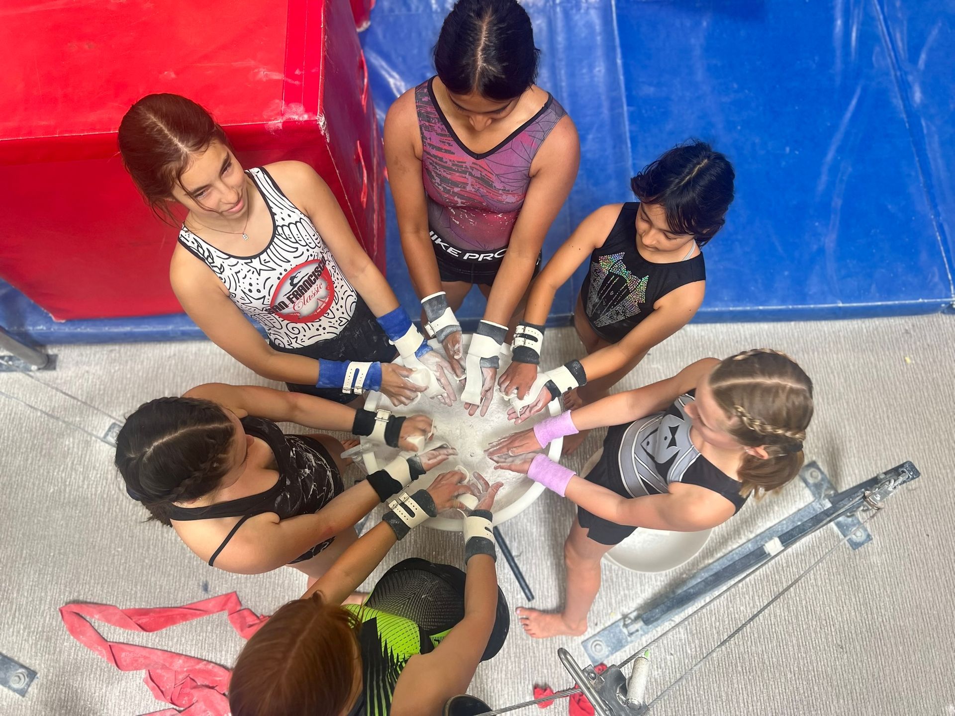 A group of girls are sitting in a circle with their hands together