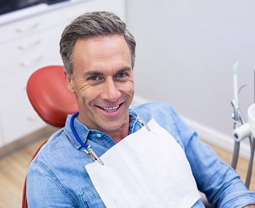 A middle aged man in a dental chair smiling