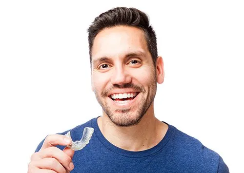 Young guy smiling and holding a Invisalign tray
