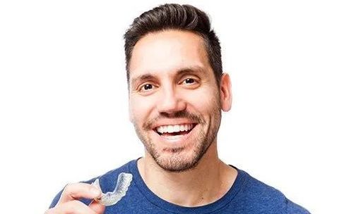 Young guy smiling and holding a Invisalign tray