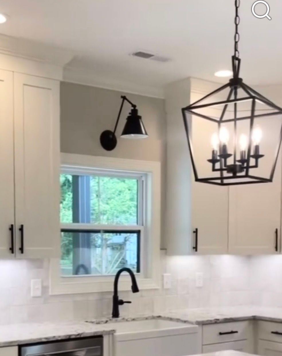 Bright modern kitchen with white cabinets, black faucet, and black pendant light above the sink