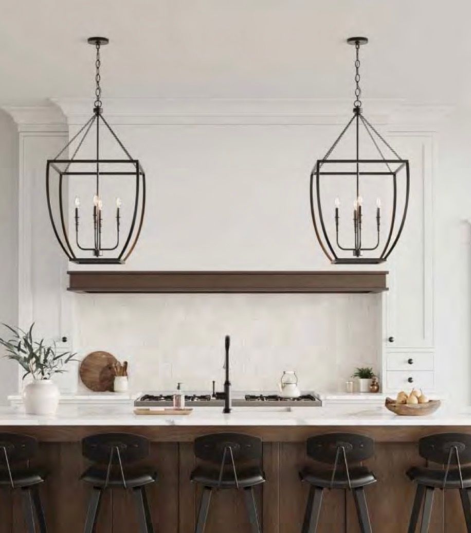 Modern white kitchen with black pendant lights, wood shelf, black island stools, and a vase of flowers