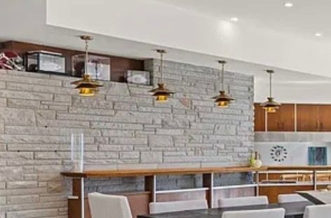 Modern dining area with stone accent wall, pendant lights, and bar seating