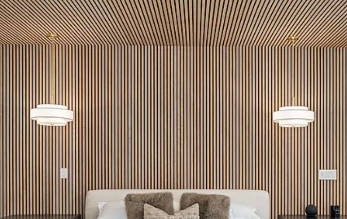 Modern bedroom with vertical wood slat wall, two white pendant lights, and a bed below.