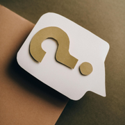 White speech bubble with a gold question mark on a tan and olive background