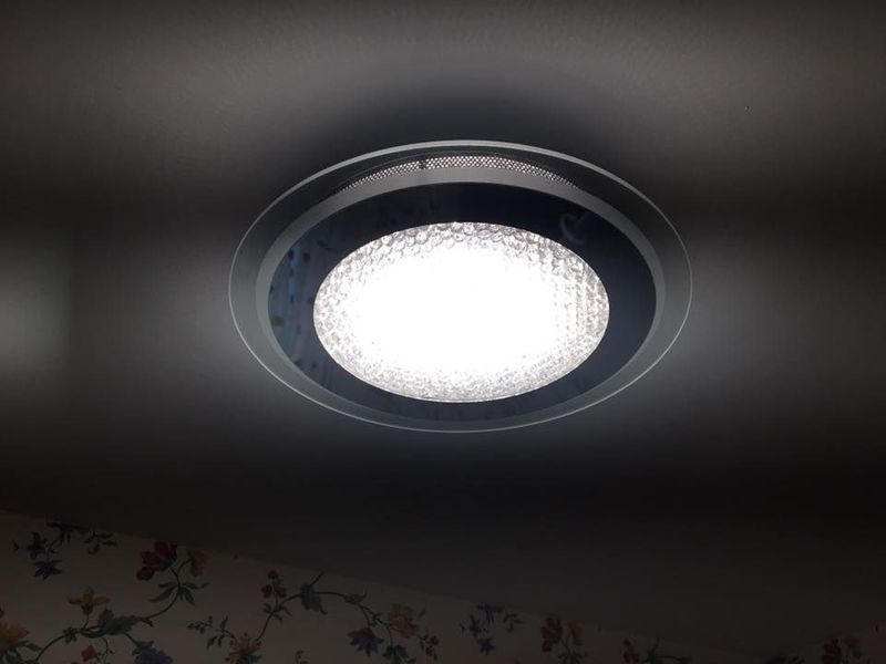 Ceiling light with a bright white center and dark circular trim against a dark ceiling