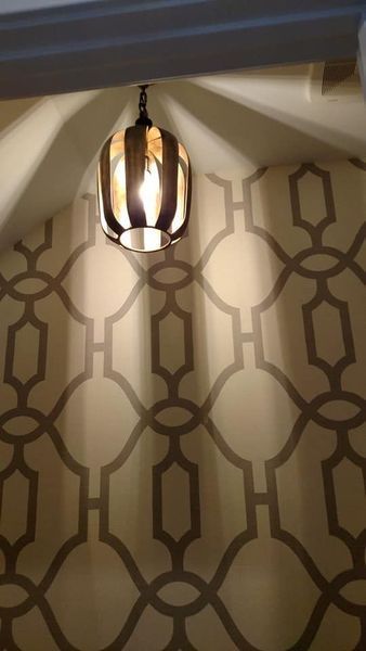Geometric wallpaper in a hallway beneath a hanging pendant light