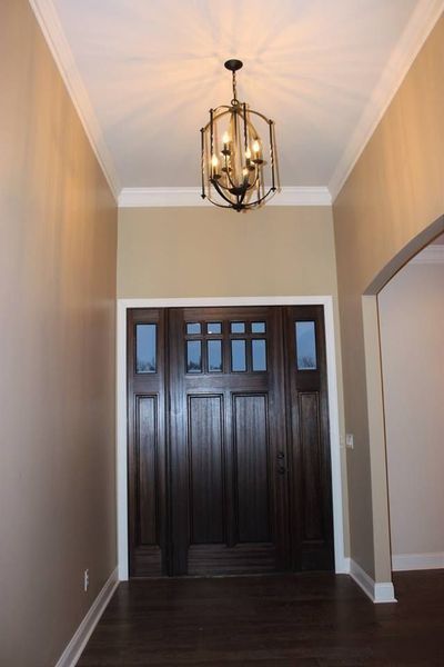 Hallway with tan walls, dark wood double doors, and a hanging lantern light fixture.